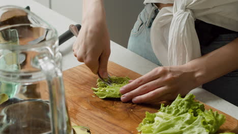 Close-Up-Of-A-Woman-Hands-Mashing-Avocado-With-A-Fork-On-A-Wooden-Chopping-Board