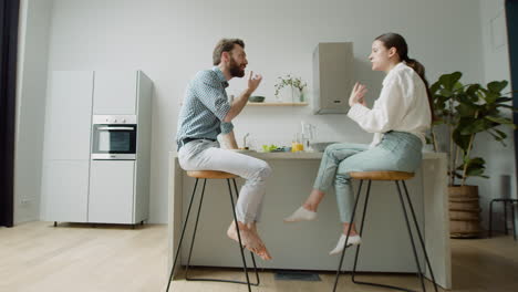 Loving-Couple-Chatting-And-Having-Lunch-Together-Sitting-On-Stool-In-A-Modern-Kitchen-1