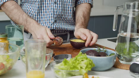 Close-Up-Of-Man-Hands-Removing-A-Pit-From-An-Avocado-With-Knife-In-A-Modern-Style-Kitchen
