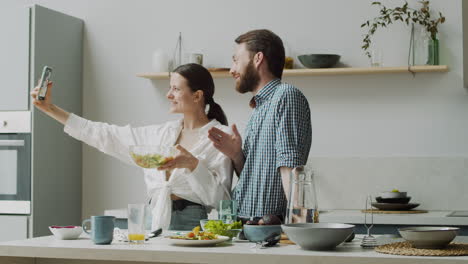 Fröhliches-Paar,-Das-In-Einer-Modernen-Küche-Ein-Selfie-Foto-Mit-Salat-Macht