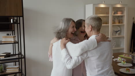 Three-Joyful-Senior-Women-Cheering-And-Hugging-At-Home