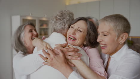 Group-Of-Cheerful-Senior-Friends-Greeting-Each-Other-With-Hugs-In-The-Kitchen-1