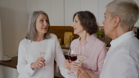 Gruppe-Fröhlicher-älterer-Freundinnen,-Die-In-Der-Küche-Reden-Und-Wein-Trinken
