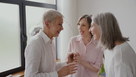 Group-Of-Cheerful-Senior-Women-Friends-Talking-And-Laughing-In-The-Living-Room