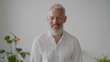 Senior-Man-With-Gray-Hair-And-White-Shirt-Looking-At-Camera-Laughing