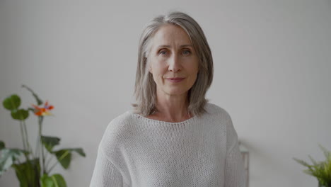 Senior-Woman-With-Gray-Hair-And-White-Shirt-Looking-At-Camera-Smiling