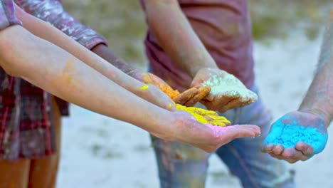 Close-Up-Of-The-Hands-Palms-Of-Young-Mixed-Races-People-Friends-Holding-Colorful-Paints-In-Powder-At-The-Holi-Fest-Celebration