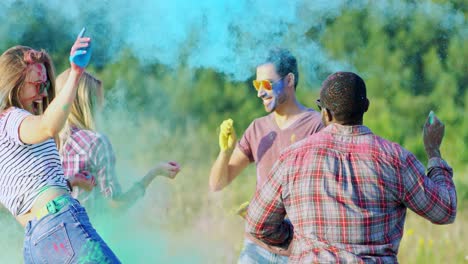 Happy-And-Cheerful-Young-Multiethnic-Guys-Spraying-Colorful-Paints-On-Their-Girlfriends-During-Holi-Fest-In-The-Field