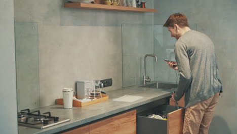 Junger-Mann,-Der-Einen-Videoanruf-Mit-Einem-Smartphone-Hat,-Während-Er-In-Der-Küche-Frühstückt