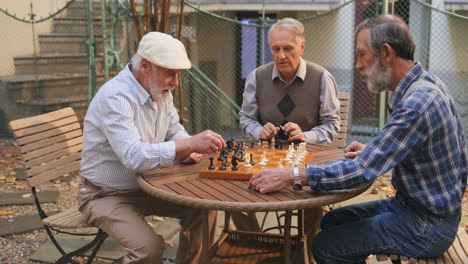 Porträtaufnahme-Des-Senioren,-Der-Mit-Einem-Schachspiel-Im-Freien-Am-Tisch-Sitzt-Und-Angestrengt-Nachdenkt