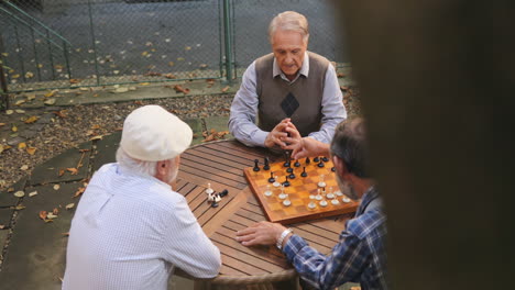 Blick-Von-Oben-Auf-Die-Pensionierten-Senioren,-Die-An-Der-Frischen-Luft-Am-Tisch-Sitzen-Und-Schach-Spielen