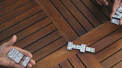 Close-Up-Of-The-Two-Old-Friends-Starting-Playing-Domino-Game-On-The-Wooden-Table-And-Doing-Their-Turns