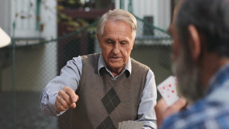 View-Over-The-Shoulder-Of-The-Old-Man-Choosing-A-Card-For-His-Turn-While-His-Friend-Making-His-Move