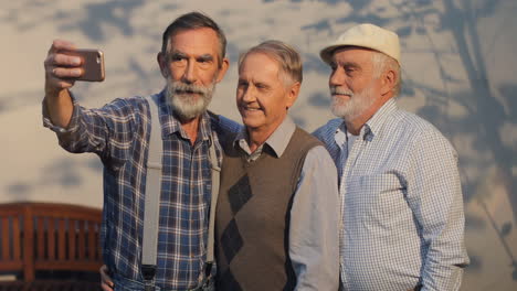 Three-Old-Men-On-Retirement-Smiling-And-Taking-A-Selfie-Photo-On-The-Smartphone-Camera