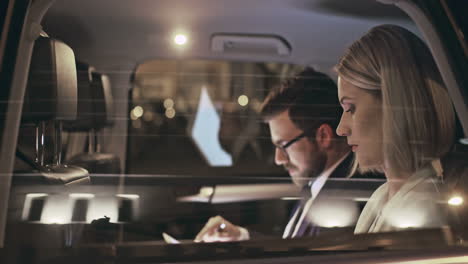 Outside-View-Of-A-Moving-Car,-A-Couple-In-Smart-Clothes-Reading-Documents