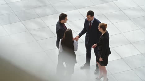 Top-View-Of-Group-Of-Workers-Dressed-In-Elegant-Clothes-Greet-Each-Other-In-The-Hall-Of-The-Office-Building