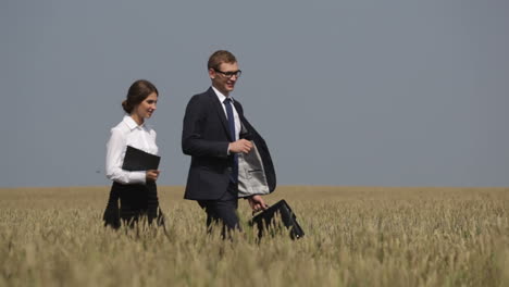 Businessman-And-Businesswoman-Walking-Through-A-Wheat-Field-While-Talking-In-Daylight