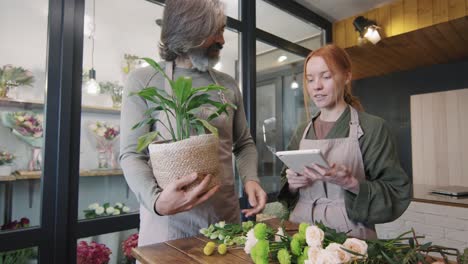 Shop-Assistant-In-Florist-Making-Flower-Arrangements-Talks-To-Her-Boss-While-Holding-A-Tablet