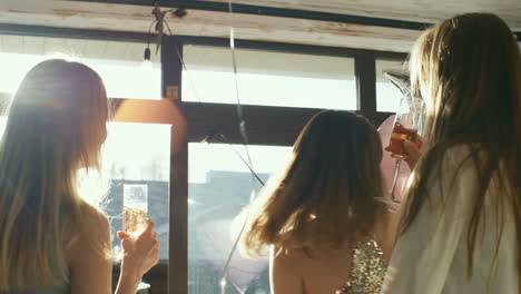 Three-Young-Women-In-Party-Dresses-Toasting-With-Champagne