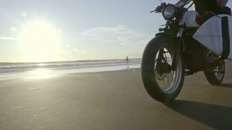 Paar-Auf-Einem-Motorrad-Mit-Einem-Surfbrett-Am-Strand