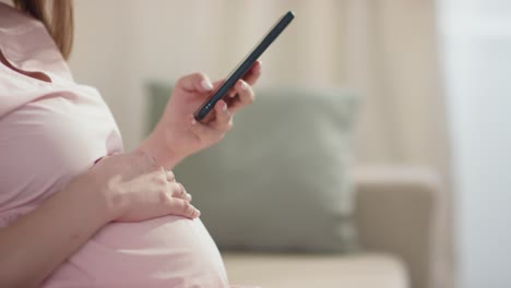 Schwangere-Frau-In-Rosafarbenem-Kleid,-Die-Auf-Das-Smartphone-Schaut
