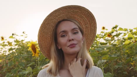 Woman-Wearing-Hat-In-A-Field-Of-Sunflowers-Posing-At-Camera