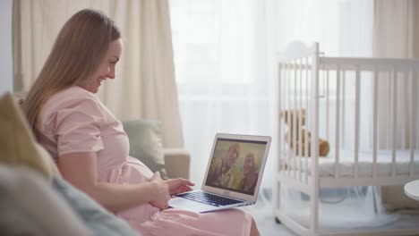 Schwangere-Frau,-Die-Auf-Dem-Sofa-Sitzt-Und-Mit-Einem-Laptop-Einen-Videoanruf-Mit-Seinen-Eltern-Macht
