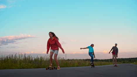 Zwei-Jungen-Und-Ein-Mädchen,-Die-Auf-Der-Straße-Mitten-Auf-Einer-Wiese-Skateboard-Fahren