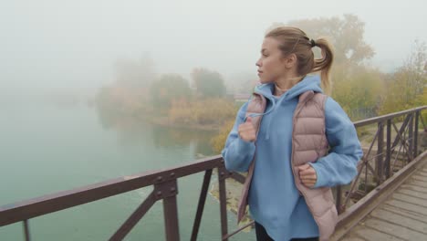 Blonde-Girl-With-Headphones-Running-On-A-Wooden-Bridge-On-A-Cloudy-Day-1
