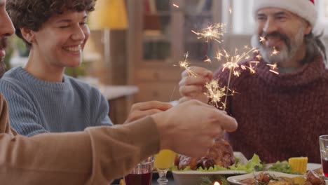 Family-Sitting-At-Table-At-Christmas-Meal-Holding-Sparklers