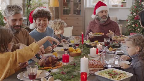Family-Sitting-At-Table-At-Christmas-Meal,-They-Pass-Dishes-To-Each-Other-And-Talk