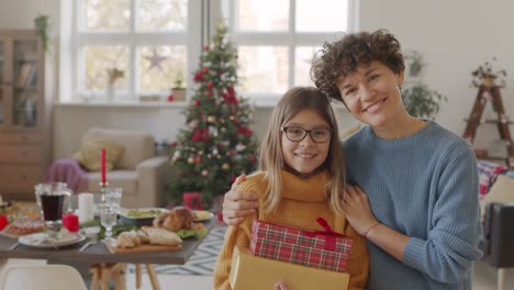 Brunette-Short-Hair-Mother-Hugs-Her-Daughter-In-The-Living-Room-With-Table-Setting-And-Christmas-Decorations