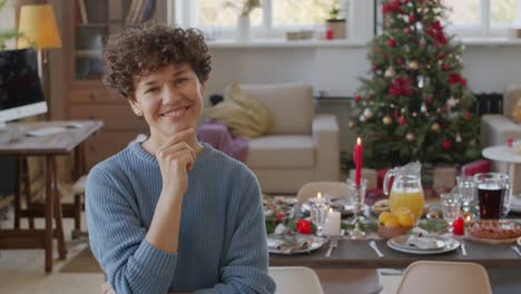 Kurze-Haare-Brünette-Lächelnde-Frau,-Die-Kamera-Im-Wohnzimmer-Mit-Tisch--Und-Weihnachtsdekoration-Anschaut