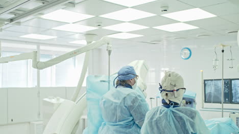 Rückansicht-Zweier-Chirurgen,-Die-In-Einem-Operationssaal-Mit-Klinischen-Instrumenten-Und-Monitoren-Operieren