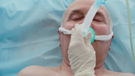 Top-View-Of-Intubated-Senior-Man-In-Hospital-Bed,-Doctor-Adjusts-Assisted-Breathing