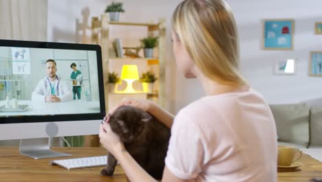 Blonde-Woman-With-Her-Black-Cat-Talking-To-A-Vet-In-An-Online-Consultation