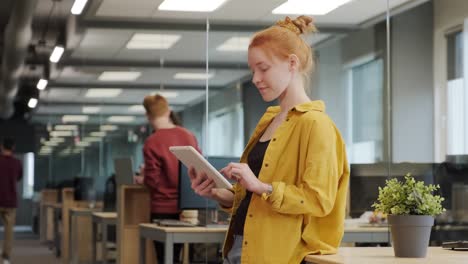 Young-Redhead-Businesswoman-In-Yellow-Jacket-Using-Tablet-In-Office