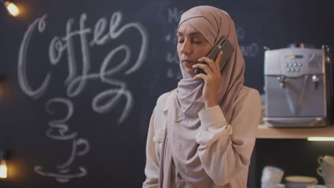 Muslim-Woman-Talking-On-The-Phone-In-A-Coffee-Shop