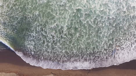 Aerial-Drone-Shot-Of-Ocean-Waves-Rolling-And-Crashing-Into-Sandy-Beach