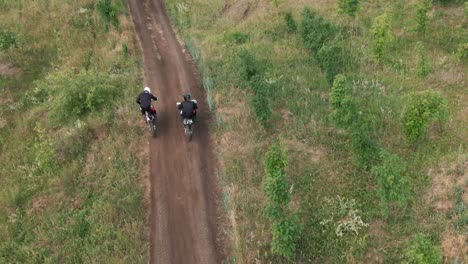 Vista-Aérea-De-Dos-Hombres-Montando-Motocross-En-Un-Camino-De-Tierra-En-El-Bosque