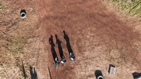 Aerial-View-Of-Three-Men-Starting-Motocross-Race-On-A-Dirt-Road-In-The-Forest