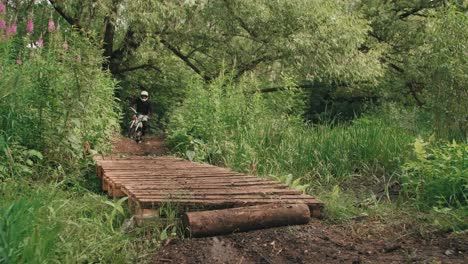 Vorderansicht-Von-Zwei-Männern,-Die-Motocross-Auf-Einer-Holzbrücke-Im-Wald-Fahren