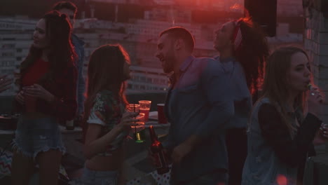 Group-Of-Friends-Enjoying-A-Party-On-A-Terrace-At-Sunset,-Everyone-Dances-And-Laughs-1