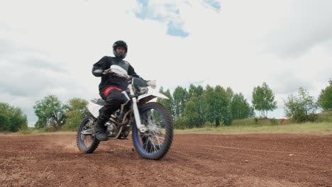 Motocross-Fahrer,-Der-Auf-Einer-Unbefestigten-Straße-Fährt-Und-In-Die-Kamera-Schaut
