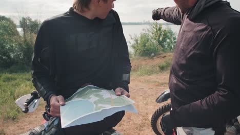 Dos-Pilotos-De-Motocross-Mirando-El-Mapa-Para-Encontrar-La-Ruta
