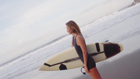 Schöne-Sportliche-Frau,-Die-Ihr-Surfbrett-An-Einem-Sandstrand-Hält