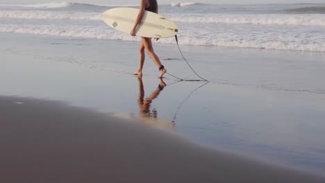 Beautiful-Sporty-Woman-Holding-Her-Surfboard-And-Walking-On-A-Sandy-Beach-1