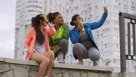 Multiethnic-Female-Friends-In-Sportswear-Smiling-And-Taking-A-Selfie-During-Break-In-Their-Running-Session