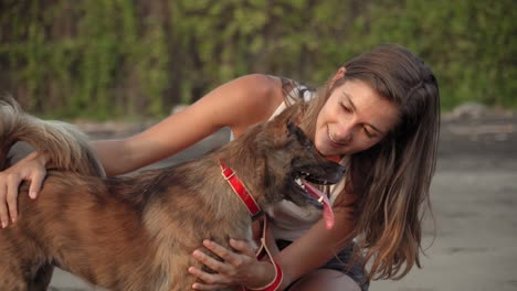 Portrait-Of-A-Pretty-Young-Woman-Petting-Her-Dog-On-The-Beach