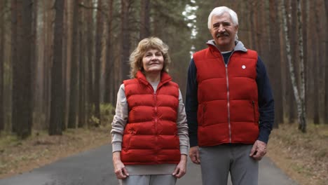 Glückliches-älteres-Paar-In-Sportkleidung,-Das-Im-Wald-In-Die-Kamera-Blickt